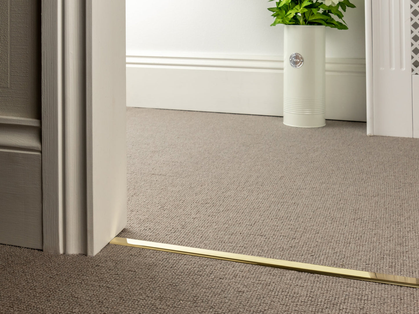 Stairrods Premier Slim D Floor Trim in brass finish installed on beige carpet flooring in interior doorway