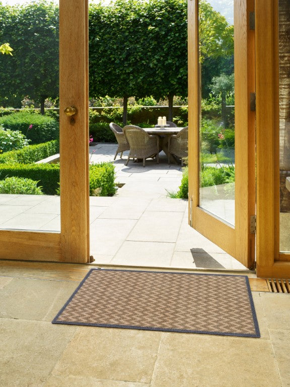 Turtle Mats Cotswold Weave Door Mat placed at open wooden door leading to garden patio