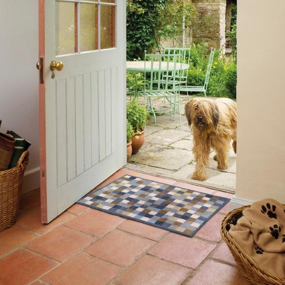 Turtle Mats Neutral Squares Indoor Floor Mat placed at open doorway with dog nearby