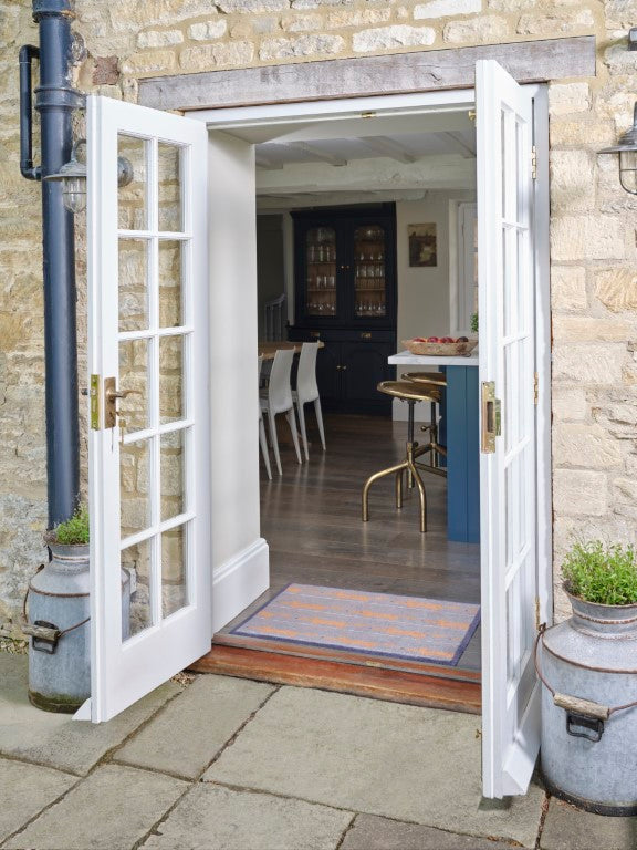Turtle Mats Running Mr Fox Design floor mat placed at open doorway of rustic stone house with wooden floor interior
