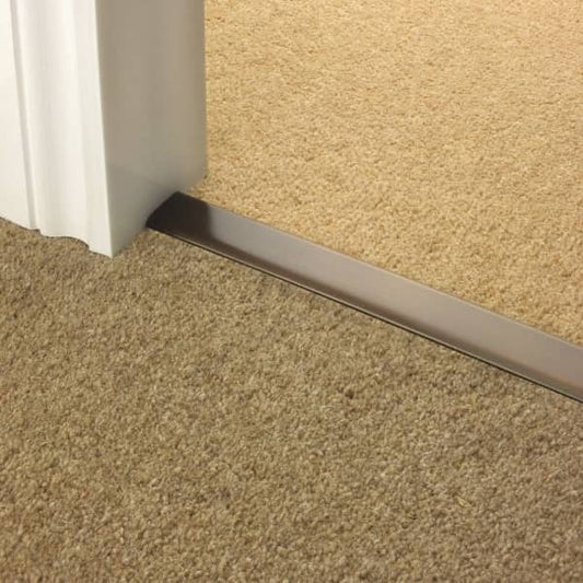 Stairrods Premier DoubleZ Flooring Trim in metal finish installed between two carpeted floors by a white door frame