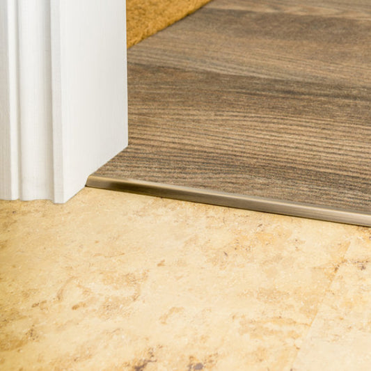 Close-up of a threshold between two different flooring materials, one wooden and one tiled.