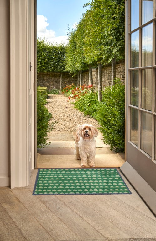 Turtle Mats Priya Door Mat with green and white pattern placed at open door entrance with small dog outside