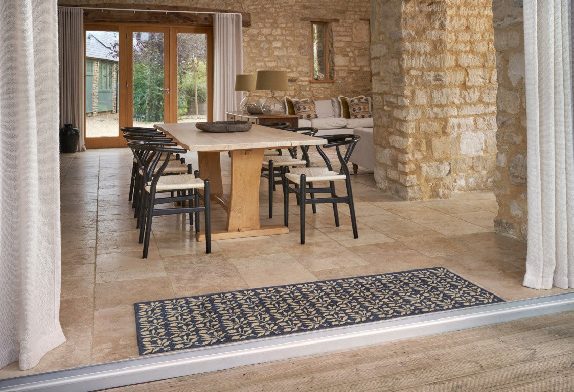 Turtle Mats - ROSEHIP Design floor mat with intricate floral pattern placed in front of a dining area in a stone-walled room