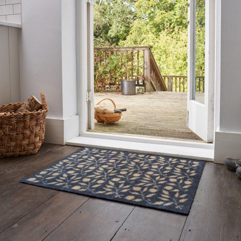 Turtle Mats - ROSEHIP Design floor mat with leaf pattern placed on wooden floor by open door