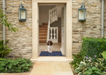 Turtle Mats Running Mr Fox Design floor mat placed at the entrance with a dog standing on it inside a stone house